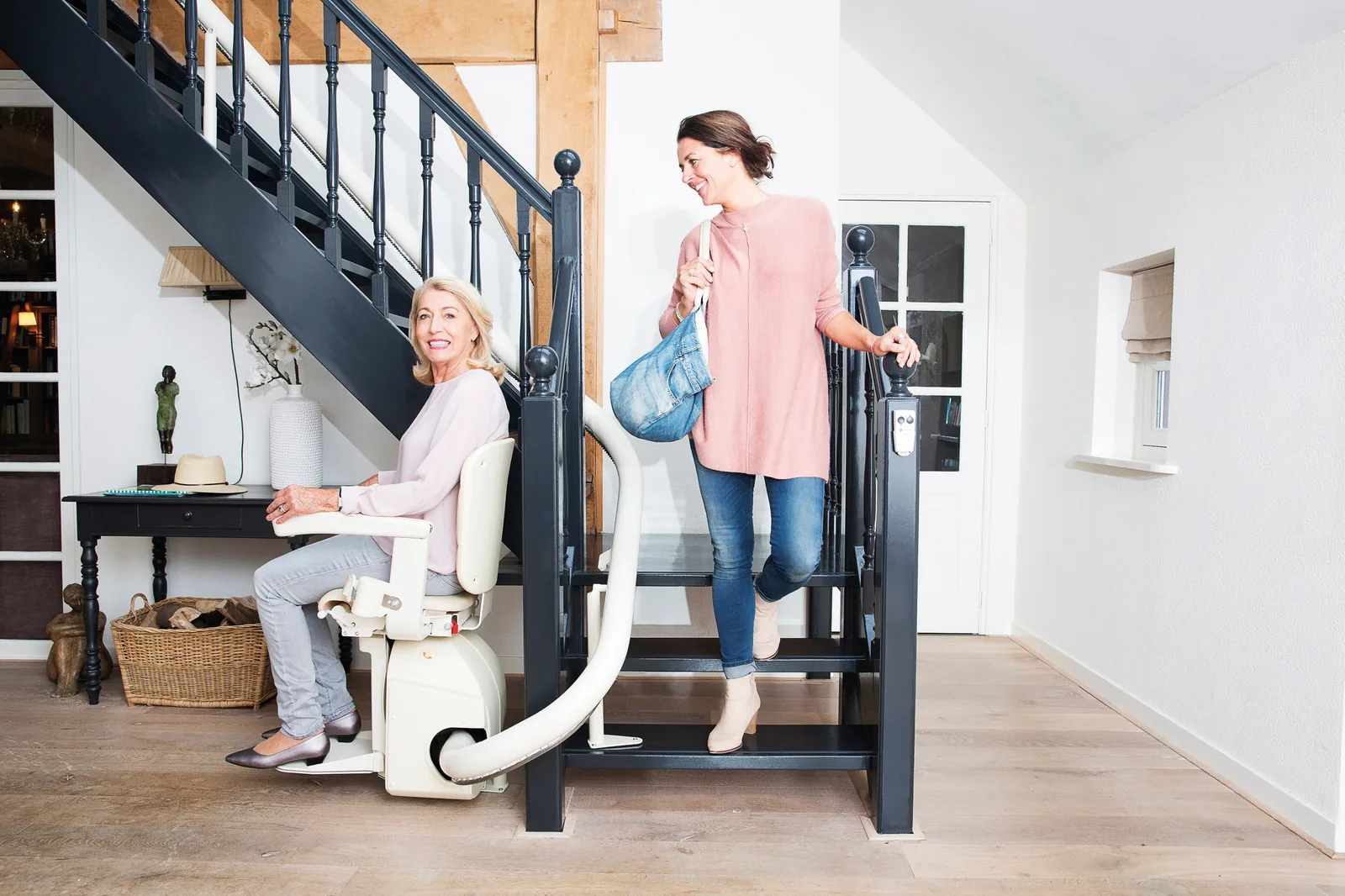 Handicare Freecurve Kurventreppenlift in einem hellen Wohnhaus mit Nutzerin und Begleitung